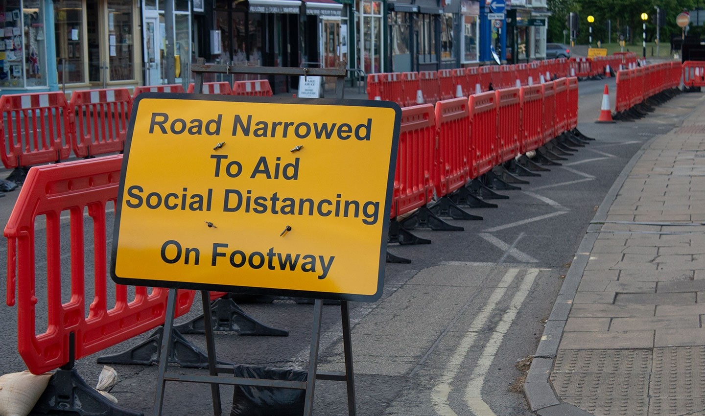A sign in the UK informs citizens that a road is half closed to allow enough social distancing space for pedestrians.